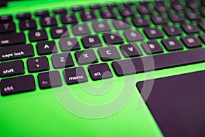 black keyboard on a green laptop. keys with letters and numbers. Detail of a laptop computer. Image detail to describe IT tools,