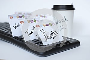 On the black keyboard many stickers with the names of the days of the week. next to a paper Cup of coffee with the inscription