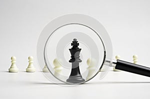 Black king chess standout with magnifier glass from white pawn chess for sign of leadership and management boss concept
