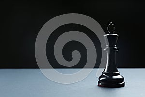 Black king on table against dark background, space for text. Chess piece