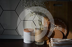 Black kitchen counter with rustic vase with dry plants near a wooden cutting board