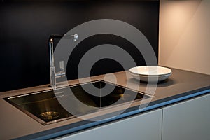 Black kitchen sink and Tap water in the kitchen. The interior of the kitchen room of the apartment. Domestic Appliances