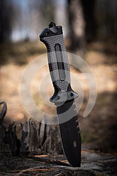 Black knife on a stump forest. Concept of outdoor recreation.