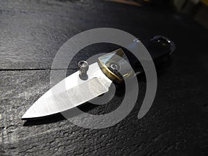 Black knife on wooden background. Edc pocket blade.