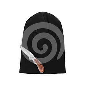 Black knitted balaclava and knife on white background, top view