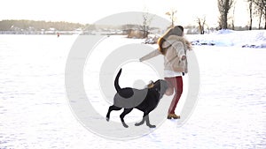 Black labrador running with young girl on snow field