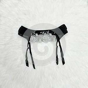 Black lace belt for stockings in female hand. Fashionable concep