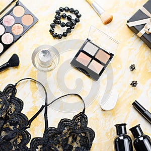 Black lace lingerie with beauty care products, make up cosmetics, jewelry in black and gold. Fashion flat lay, top view