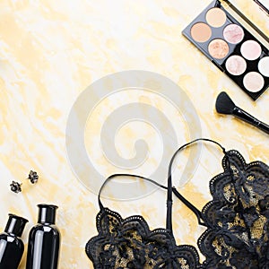 Black lace lingerie with beauty care products, make up cosmetics, jewelry in black and gold. Fashion flat lay, top view