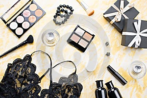 Black lace lingerie with beauty care products, make up cosmetics, jewelry in black and gold. Fashion flat lay, top view