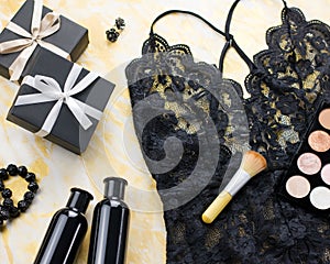 Black lace lingerie with beauty care products, make up cosmetics, jewelry in black and gold. Fashion flat lay, top view