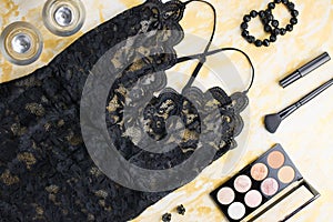 Black lace lingerie with beauty care products, make up cosmetics, jewelry in black and gold. Fashion flat lay, top view