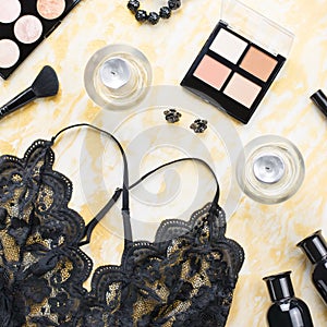 Black lace lingerie with beauty care products, make up cosmetics, jewelry in black and gold. Fashion flat lay, top view