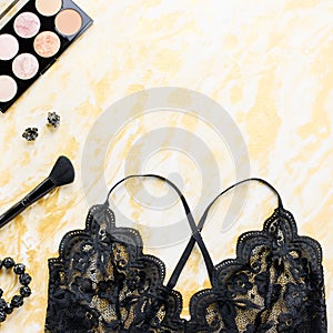 Black lace lingerie with beauty care products, make up cosmetics, jewelry in black and gold. Fashion flat lay, top view