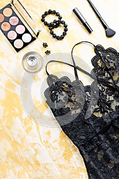 Black lace lingerie with beauty care products, make up cosmetics, jewelry in black and gold. Fashion flat lay, top view