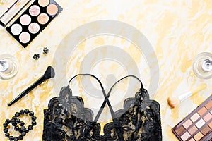 Black lace lingerie with beauty care products, make up cosmetics, jewelry in black and gold. Fashion flat lay, top view