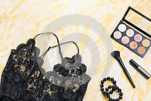 Black lace lingerie with beauty care products, make up cosmetics, jewelry in black and gold. Fashion flat lay, top view