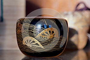 Black lacquer tea caddie with cart wheel design and waves in gold from Japan