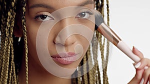 Black Lady Applying Powder With Cosmetic Brush Over White Background