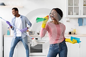 Black lady having fun with her boyfriend while cleaning kitchen