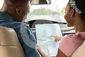 Black lady helping her driving boyfriend, checking map, back view