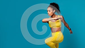 black lady performing dynamic fitness exercise jumping over blue background