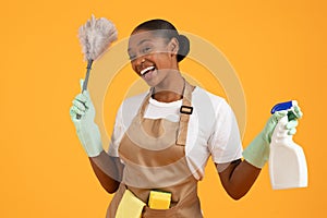 black lady poses with cleaning tools against bright yellow backdrop