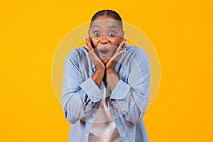 black lady shouting in excitement touching face over yellow background