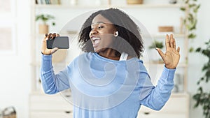 Black lady singing using smartphone as mic