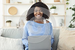 Black lady sitting on couch and working on pc