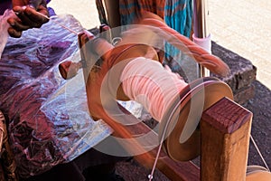 Black lady spinning silk on an wooden spinning wheel