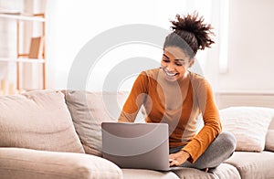 Black Lady Using Laptop Sitting On Sofa At Home