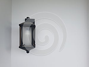 A black lamp is mounted on a white wall in the corner.