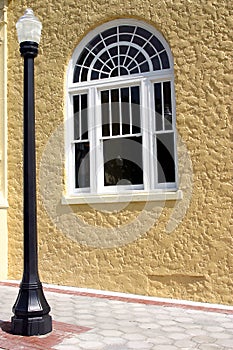 Black lamppost and window against yellow stucco wall