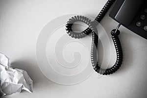 Black land line telephone and white crumpled paper on textured granite surface