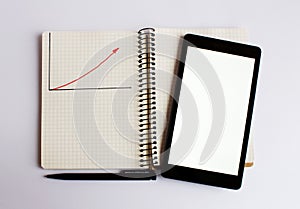 Black laptop lies on the opened notebook. A red up arrow is drawn on the notebook.