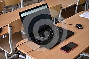 A black laptop and a phone on the desktop. An office workplace with a computer