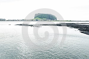 Black lava formation from white lake view to Ilchulbong volcano crater, Seongsan, Jeju Island, South Korea