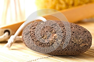 Black lava pumice stone with natural spa or bath utensils used for peeling or callused skin removal on bamboo mat background