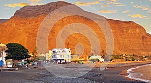 Black lava sand beach, small town at foot of red mighty rock face, sunset sky - La Puntilla, Valle Gran Rey, La Gomera photo