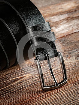 Black leather belt on a wooden brown background