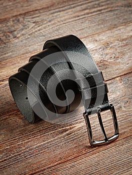 Black leather belt on a wooden brown background