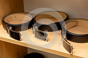 Black leather belts display on shelf in the store in a men clothing boutique