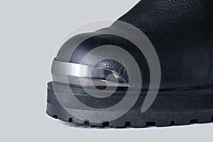 Black leather boot close up with metal plates in front on white background