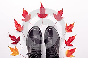 Black leather boots and red leaves on white background. Autumn sale concept. Top view