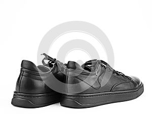 Black leather classic sneakers with laces. Casual men's style. Black rubber soles. Isolated close-up on white