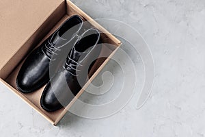 Black Leather men's shoes in brown box on gray stone background. Flat lay top view