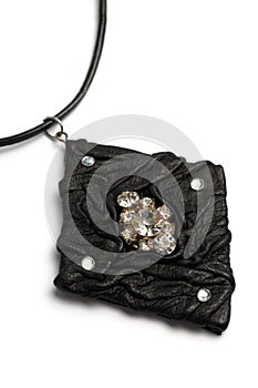 Black leather pendant with precious stones in the shape of a lozenge on a white background