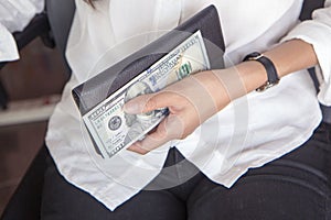 Black leather purse with hundred dollar banknote in young woman