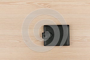 Black leather purse lying on a wooden table.